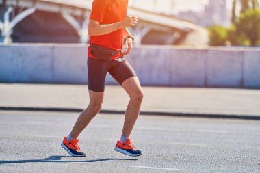 Koşan adam. Şehir yolunda spor kıyafetleriyle koşan atletik bir adam. Sağlıklı yaşam tarzı, spor hobisi. Sokak çalışması, açık hava koşusu.