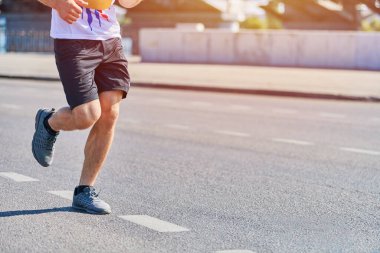 Koşan adam. Şehir yolunda spor kıyafetleriyle koşan atletik bir adam. Sağlıklı yaşam tarzı, spor hobisi. Sokak çalışması, açık hava koşusu.