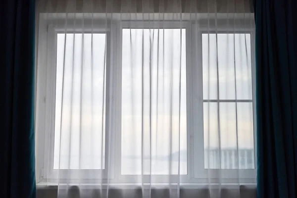 Windows with curtains in rental apartment. Cityscape view. Light window in the room