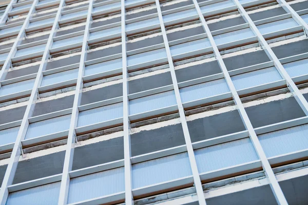 Multistorey building. Rhythm in photography. Multi-storey facade, windows and block of flats, close up. Modern apartments in high raised building. Angle perspective.