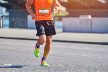 Koşan adam. Şehir yolunda spor kıyafetleriyle koşan atletik bir adam. Sağlıklı yaşam tarzı, spor hobisi. Sokak çalışması, açık hava koşusu.