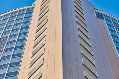 Çok katlı bir bina. Fotoğrafçılıkta ritim. Çok katlı cephe, pencereler ve apartman blokları, kapatın. Yüksek binadaki modern daireler. Bakış açısı.