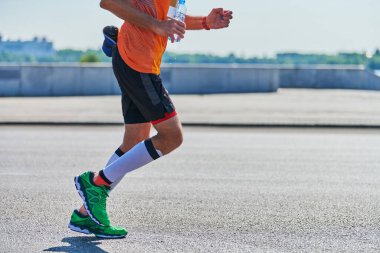 Koşan adam. Şehir yolunda spor kıyafetleriyle koşan atletik bir adam. Sağlıklı yaşam tarzı, spor hobisi. Sokak çalışması, açık hava koşusu.