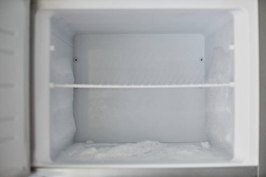 Ice buildup in freezer. Broken frozen refrigerator with built up ice and frost. Empty freezer drain is clogged. clipart