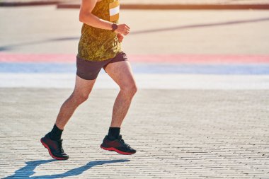 Koşan adam. Şehir yolunda spor kıyafetleriyle koşan atletik bir adam. Sağlıklı yaşam tarzı, spor hobisi. Sokak çalışması, açık hava koşusu.