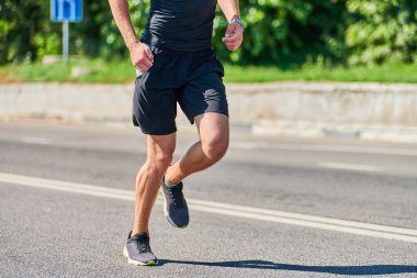Koşan adam. Şehir yolunda spor kıyafetleriyle koşan atletik bir adam. Sağlıklı yaşam tarzı, spor hobisi. Sokak çalışması, açık hava koşusu.