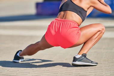 Genç bir kadın maraton koşmadan önce ısınıyor. Bronz bacaklı güzel bir kız. Açık hava fitness germe egzersizi. Spor partisi.