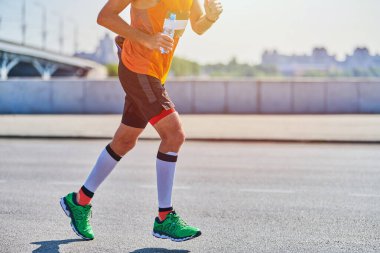 Koşan adam. Şehir yolunda spor kıyafetleriyle koşan atletik bir adam. Sağlıklı yaşam tarzı, spor hobisi. Sokak çalışması, açık hava koşusu.
