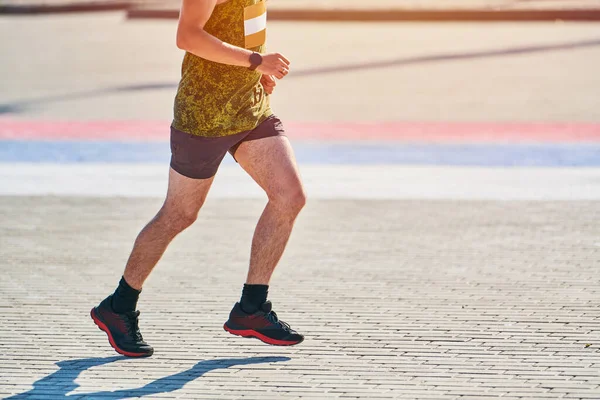 Koşan adam. Şehir yolunda spor kıyafetleriyle koşan atletik bir adam. Sağlıklı yaşam tarzı, spor hobisi. Sokak çalışması, açık hava koşusu.