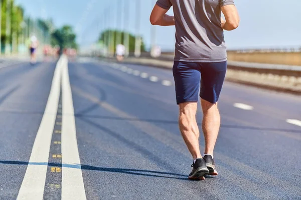 Koşan adam. Şehir yolunda spor kıyafetleriyle koşan atletik bir adam. Sağlıklı yaşam tarzı, spor hobisi. Sokak çalışması, açık hava koşusu.