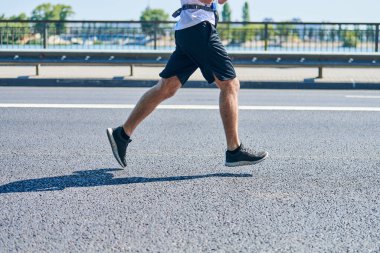 Koşan adam. Şehir yolunda spor kıyafetleriyle koşan atletik bir adam. Sağlıklı yaşam tarzı, spor hobisi. Sokak çalışması, açık hava koşusu.