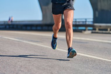 Koşan adam. Şehir yolunda spor kıyafetleriyle koşan atletik bir adam. Sağlıklı yaşam tarzı, spor hobisi. Sokak çalışması, açık hava koşusu.