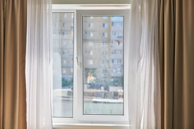Dairenin kirli penceresi. Yıkanmamış tozlu cam, şehir manzaralı arka plan. Kirli çift camlı pencere