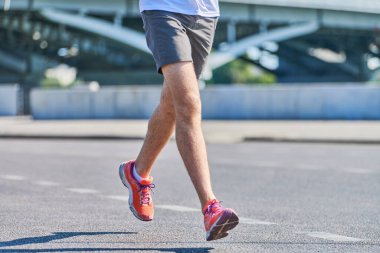 Koşan adam. Şehir yolunda spor kıyafetleriyle koşan atletik bir adam. Sağlıklı yaşam tarzı, spor hobisi. Sokak çalışması, açık hava koşusu.