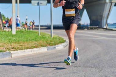 Koşan adam. Şehir yolunda spor kıyafetleriyle koşan atletik bir adam. Sağlıklı yaşam tarzı, spor hobisi. Sokak çalışması, açık hava koşusu.