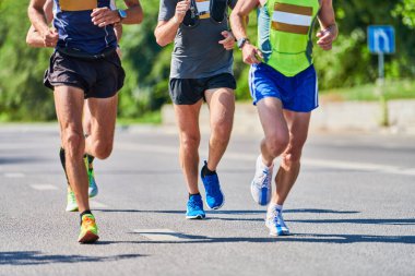 Koşan adamlar. Şehir yolunda spor kıyafetleriyle koşan spor adamları. Sağlıklı yaşam tarzı, spor hobisi. Sokak maratonu, açık hava koşusu.