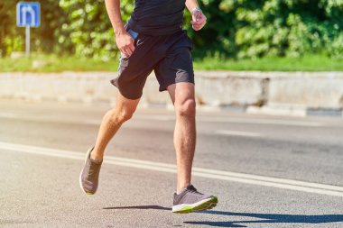 Koşan adam. Şehir yolunda spor kıyafetleriyle koşan atletik bir adam. Sağlıklı yaşam tarzı, spor hobisi. Sokak çalışması, açık hava koşusu.