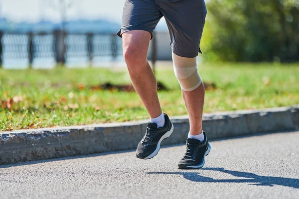 Koşan adam. Şehir yolunda spor kıyafetleriyle koşan atletik bir adam. Sağlıklı yaşam tarzı, spor hobisi. Sokak çalışması, açık hava koşusu.