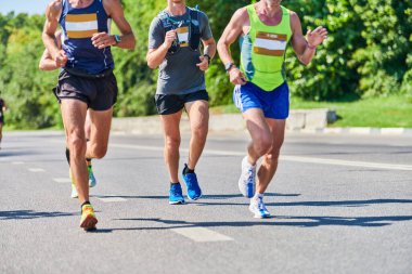 Koşan adamlar. Şehir yolunda spor kıyafetleriyle koşan spor adamları. Sağlıklı yaşam tarzı, spor hobisi. Sokak maratonu, açık hava koşusu.
