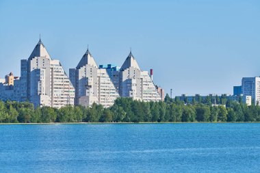 Çok katlı piramit evleri nehrin üzerini görüyor. Kiralık daireler için çok katlı gökdelenler. Piramit tasarım tarzı. Nehir kıyısındaki küçük şehir.