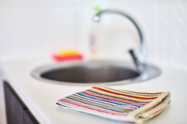 Kitchen towel and sink without dirty dishes background. Dishcloth on kitchen countertop. Cleaning and dish washing concept. clipart