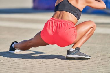 Genç bir kadın maraton koşmadan önce ısınıyor. Bronz bacaklı güzel bir kız. Açık hava fitness germe egzersizi. Spor partisi.