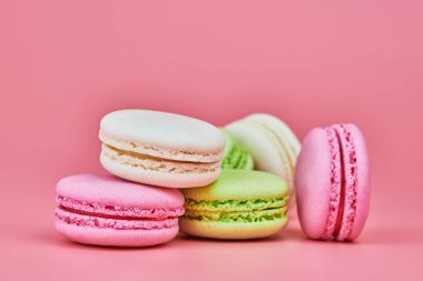 Pembe arka planda makarnalar. Badem ve hindistan cevizinden renkli küçük kurabiyeler. Popüler şekerlemeler. Atıştırmalık lezzetli yemekler, kopyalama alanı