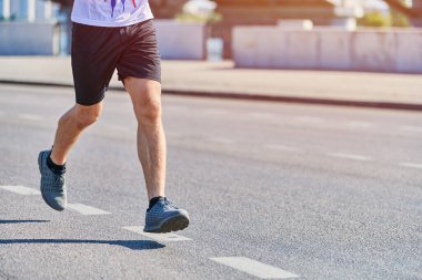 Koşan adam. Şehir yolunda spor kıyafetleriyle koşan atletik bir adam. Sağlıklı yaşam tarzı, spor hobisi. Sokak çalışması, açık hava koşusu.