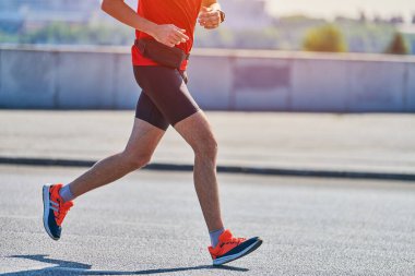 Koşan adam. Şehir yolunda spor kıyafetleriyle koşan atletik bir adam. Sağlıklı yaşam tarzı, spor hobisi. Sokak çalışması, açık hava koşusu.