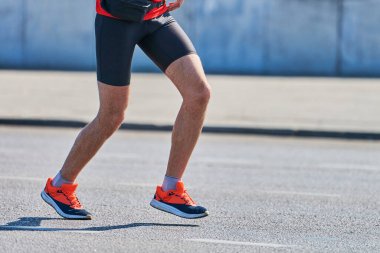 Koşan adam. Şehir yolunda spor kıyafetleriyle koşan atletik bir adam. Sağlıklı yaşam tarzı, spor hobisi. Sokak çalışması, açık hava koşusu.