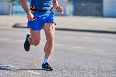 Koşan adam. Şehir yolunda spor kıyafetleriyle koşan atletik bir adam. Sağlıklı yaşam tarzı, spor hobisi. Sokak çalışması, açık hava koşusu.