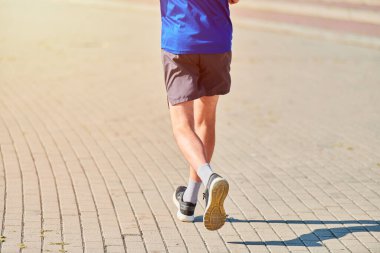 Koşan adam. Şehir yolunda spor kıyafetleriyle koşan atletik bir adam. Sağlıklı yaşam tarzı, spor hobisi. Sokak çalışması, açık hava koşusu.