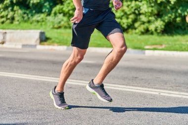 Koşan adam. Şehir yolunda spor kıyafetleriyle koşan atletik bir adam. Sağlıklı yaşam tarzı, spor hobisi. Sokak çalışması, açık hava koşusu.