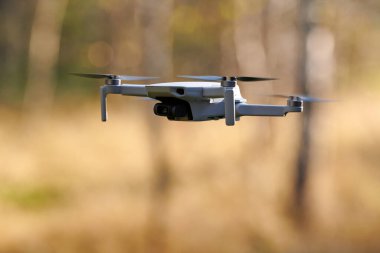 Gökyüzünde bir kuadkopter drone var. Küçük İHA gökyüzünde uçup video ve fotoğraf çekiyor. Uzaktan kumandalı hava dağıtımı ve casus.