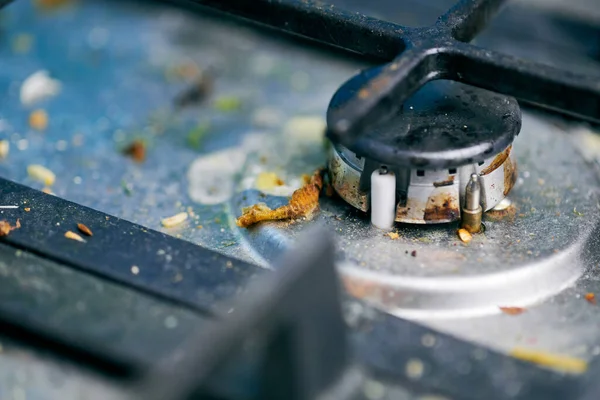 Dirty stove top with oil splatters, fat stains and food leftovers. Unclean steel kitchen cooktop with greasy spots. Spring-cleaning, removing kitchen old stains, fry spots, crumbs and burned-on bits