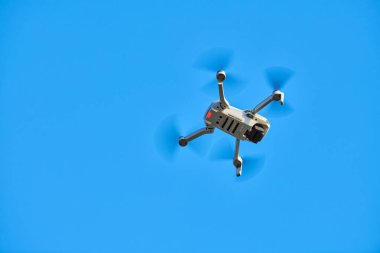 Gökyüzünde bir kuadkopter drone var. Küçük İHA gökyüzünde uçup video ve fotoğraf çekiyor. Uzaktan kumandalı hava dağıtımı ve casus.