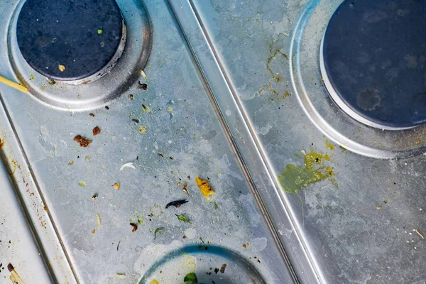 Dirty stove top with oil splatters, fat stains and food leftovers. Unclean steel kitchen cooktop with greasy spots. Spring-cleaning, removing kitchen old stains, fry spots, crumbs and burned-on bits