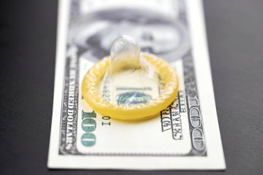 Prezervatif ve Amerikan doları. Fuhuş konsepti. Gecelik seks için para öde. Fahişelik ve fahişelik. Gebelik önleyicili masada Amerikan Doları parası.