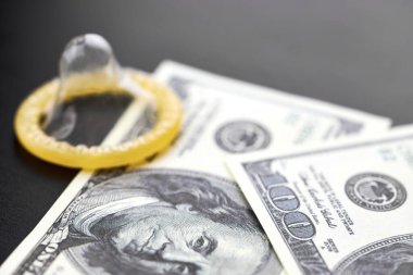 Prezervatif ve banknot. Fuhuş konsepti. Doğum kontrol hapı olan bir Amerikan doları. Gecelik seks için para öde. Fahişelik ve fahişelik..