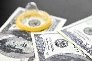 Prezervatif ve Amerikan doları. Fuhuş konsepti. Gecelik seks için para öde. Fahişelik ve fahişelik. Gebelik önleyicili masada Amerikan Doları parası.