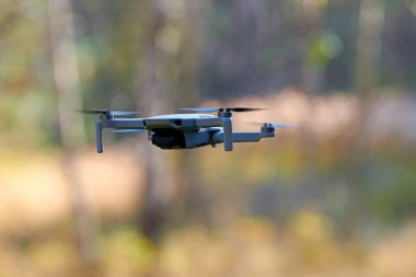 Gökyüzünde bir kuadkopter drone var. Küçük İHA gökyüzünde uçup video ve fotoğraf çekiyor. Uzaktan kumandalı hava dağıtımı ve casus.