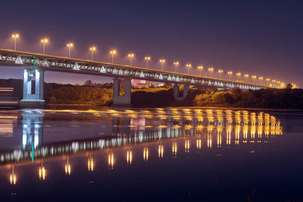 Night city bridge lighting. Beautiful reflection of night lights on water surface. Long exposure photography.