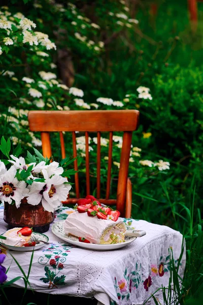 在夏日花园的桌子上放有草莓和奶油的海绵卷 老式风格 有选择的焦点 — 图库照片