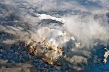 Bulutlarla kaplı karlı dağların havadan görünümü