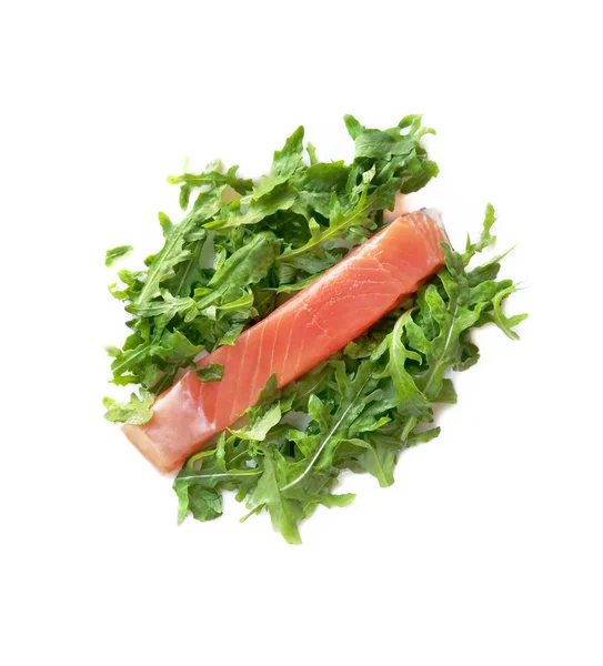 Trancher, un morceau de saumon rouge avec des feuilles vertes de roquette sur un fond blanc . — Photo