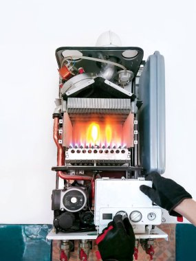 Checking double-circuit gas boiler with open lid and fire before season. Cleaning hot water heating system. clipart