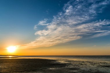 ufuk ulaşan bulutlar ile deniz sahil üzerinde güzel gün batımı