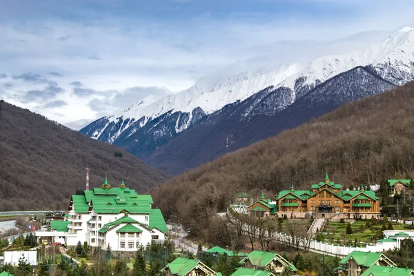 A modern cottage community with a house with green roofs located among the mountains.