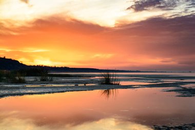 Deniz kıyısında günbatımı. Bulutlar su güzel yansıması.