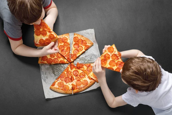 Family eating peperoni pizza. Kids holding a slice of pizza.